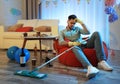 Young man with mop suffering from hangover in room after party Royalty Free Stock Photo