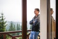 A young man looks out from the hotel`s balcony with a view of the mountains, the fog and the fir forest. Royalty Free Stock Photo