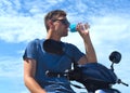 Young man a motorbike driver drinking water from a plastic bottle Royalty Free Stock Photo