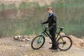 Young man on mountain bike relaxes, on background flooded mine