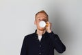 A young man with a mug of tea or coffee. He pleased. White background. Redhead male with white mug. Royalty Free Stock Photo