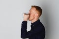 A young man with a mug of tea or coffee. He pleased. White background. Redhead male with white mug. Royalty Free Stock Photo