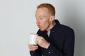 A young man with a mug of tea or coffee. He pleased. White background. Redhead male with white mug. Royalty Free Stock Photo