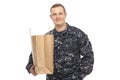 Young man in navy uniform with grocery store paper bag