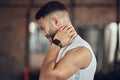 Young man with neck pain in the gym. Fit athlete with a stiff neck in the gym. Bodybuilder with a stiff neck in the gym Royalty Free Stock Photo