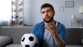 Young man nervously watching football match on tv home, frustrated at team loss