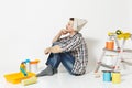 Young man in newspaper hat sitting on floor with instruments for renovation apartment room isolated on white background Royalty Free Stock Photo