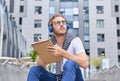 Young man with notebook, diary or sketchbook writing or drawing in city Royalty Free Stock Photo