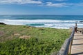 Young man observing waves on wooden pathway on beautiful atlantic coast