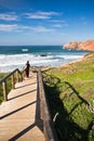Young man observing waves on wooden pathway on beautiful atlantic coast