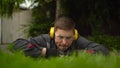 A young man obsessed with work from the special services cuts the lawn with scissors. A man in glasses and headphones Royalty Free Stock Photo