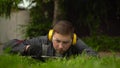 A young man obsessed with work from the special services cuts the lawn with scissors. A man in glasses and headphones Royalty Free Stock Photo