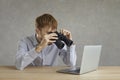 Young man office employee looking at laptop screen through binocular studio shot Royalty Free Stock Photo