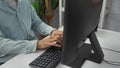 Young man in office typing on keyboard at a computer, displaying focus and productivity in a modern workplace environment with Royalty Free Stock Photo
