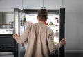 Young man opening refrigerator, back view Royalty Free Stock Photo