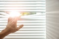 Young man opening window blinds. Space for text Royalty Free Stock Photo