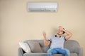 Young man operating air conditioner while sitting Royalty Free Stock Photo