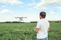 Young man operating of flying drone octocopter at the green field. Royalty Free Stock Photo