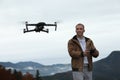 Young man operating modern drone with remote control in mountains Royalty Free Stock Photo