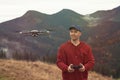 Young man operating modern drone with remote control in mountains Royalty Free Stock Photo