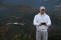 Young man operating modern drone with remote control in mountains Royalty Free Stock Photo