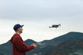 Young man operating modern drone with remote control in mountains Royalty Free Stock Photo