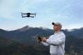 Young man operating modern drone with remote control in mountains Royalty Free Stock Photo