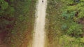 Young man operating a photography drone, high angle view from above a forest road