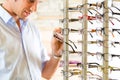 Young man at optician with glasses Royalty Free Stock Photo