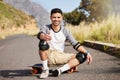 Young man outdoor, skateboard and skater with fitness on country road with smile in portrait and extreme sport