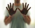 Young man with outstretched hands behind the glass