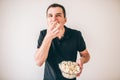 Young man over white background. Guy eating popcorn from bowl. Tasty delisious snack. Glutton man divour meal.