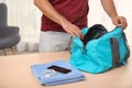 Young man packing sports bag on table Royalty Free Stock Photo