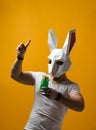 Young man in paper rabbit mask and white t-shirt drinking green cocktail drink Royalty Free Stock Photo