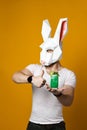 Young man in paper rabbit mask and white t-shirt drinking green cocktail drink Royalty Free Stock Photo