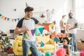 young man in party hat holding string with party garlands and friends standing behind