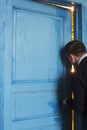 Young man peeking in the door slot.