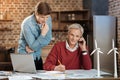 Young man peeking at notebook of his colleague calling someone Royalty Free Stock Photo