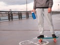 Young man on a penny board with a reusable plastic bottle in his hands