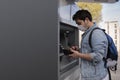 The young man performs his transactions from the bank atm using his protective mask