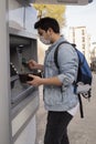 The young man performs his transactions from the bank atm using his protective mask