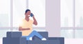 Young man phone calling african american guy sitting couch using smartphone communication concept modern living room Royalty Free Stock Photo