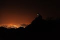 Young man with phone on top of the hill observing the night city view. Royalty Free Stock Photo