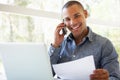 Young Man On Phone Using Laptop At Home Royalty Free Stock Photo