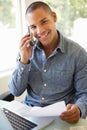 Young Man On Phone Using Laptop At Home Royalty Free Stock Photo
