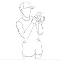 A young man photographer in a baseball cap takes a photo camera