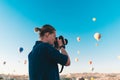 Young man photographer making pictures of air balloons at sunrise time in Cappadocia