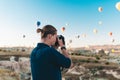 Young man photographer making pictures of air balloons at sunrise time in Cappadocia