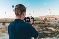 Young man photographer making pictures of air balloons at sunrise time in Cappadocia