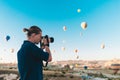 Young man photographer making pictures of air balloons at sunrise time in Cappadocia